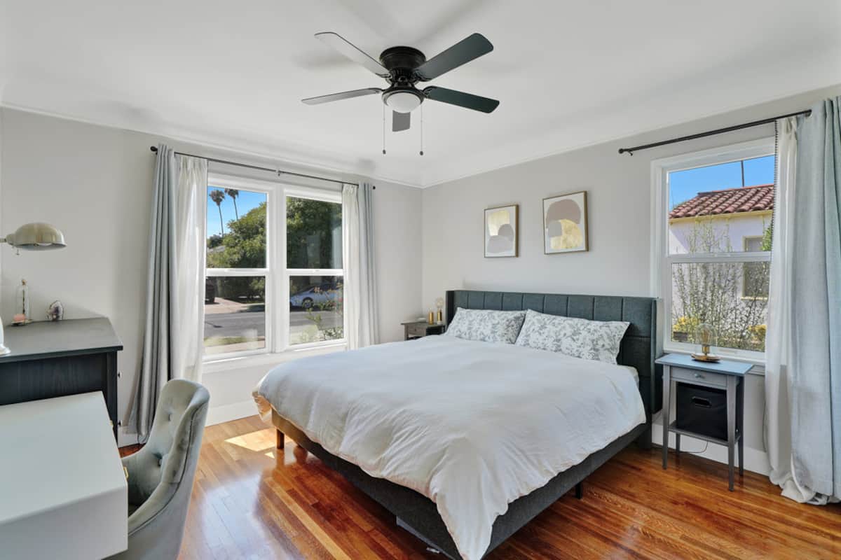 The main bedroom with a King bed, ceiling fan and sunny windows