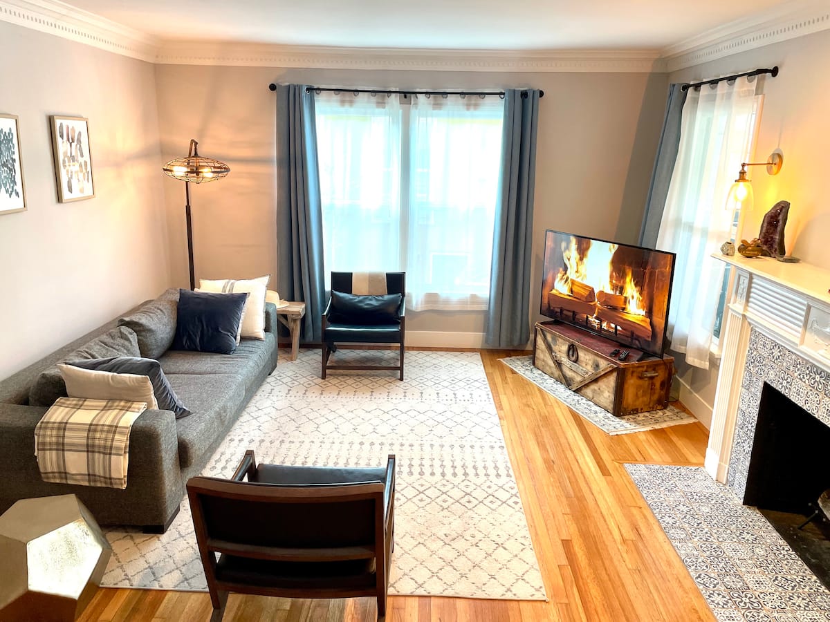 The living room at night, lit by lamps, with the fireplace glowing