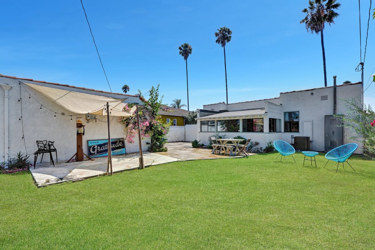 The private back garden with lawn, palm trees and a sun canopy