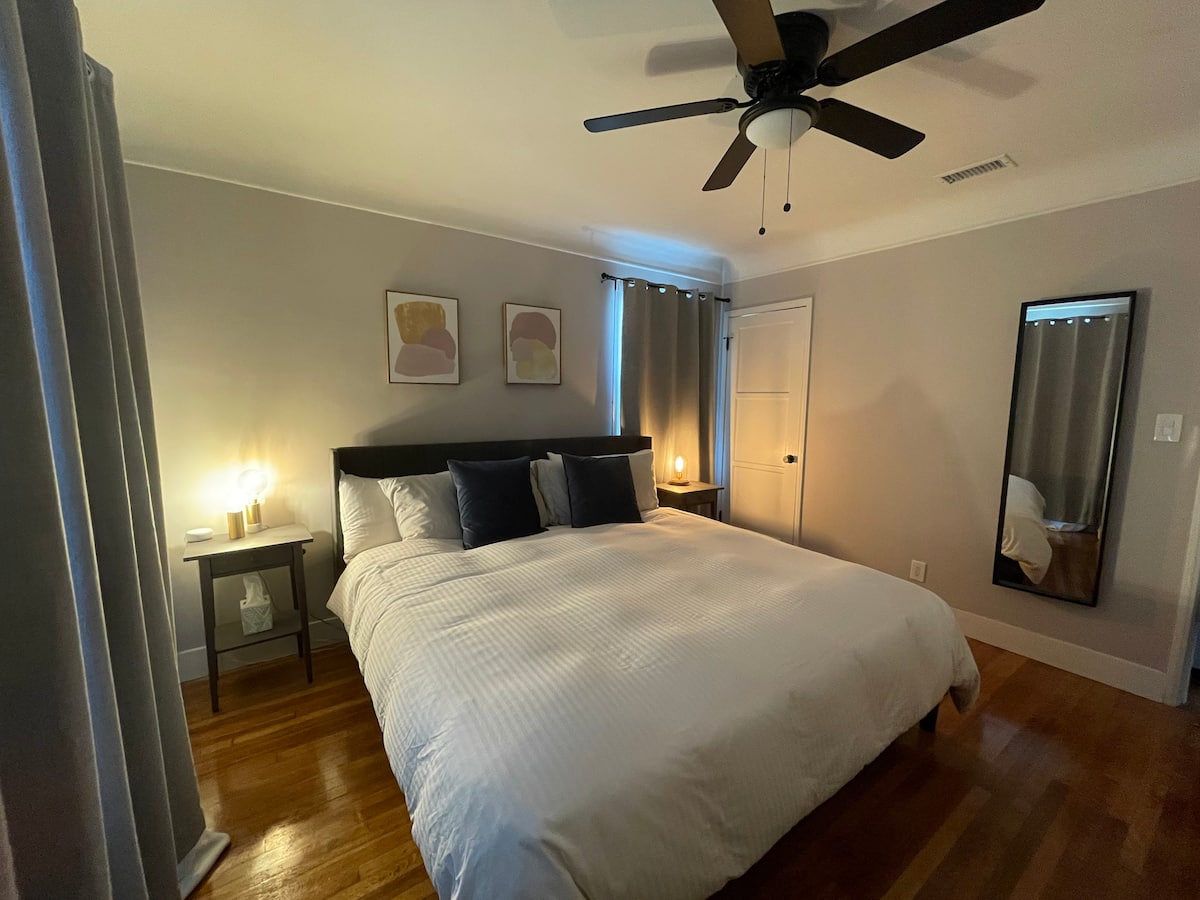 A bedroom in warm evening lamplight with dark navy bedding