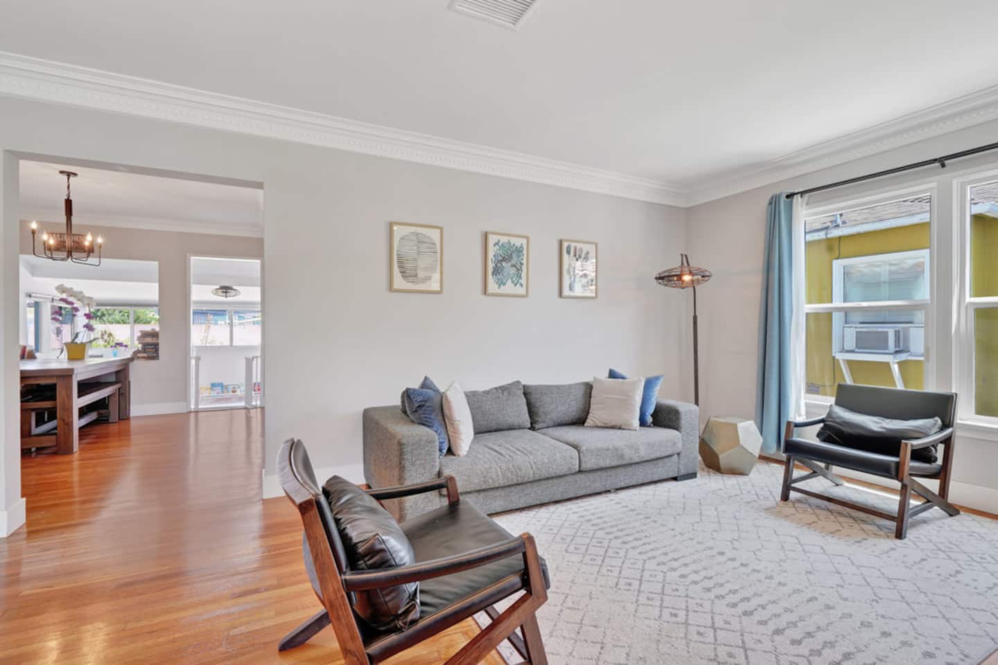 The bright lounge with a grey sofa, leather chairs and wooden floors
